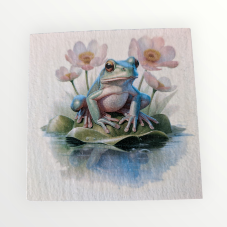 A blue frog sitting on a lily pad surrounded by pink flowers.